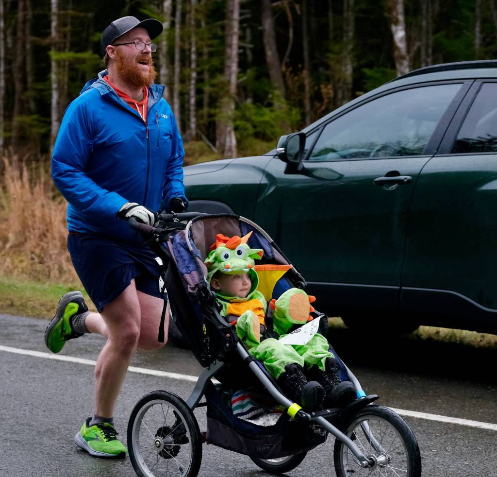 Finn Peterson, 2, edges out father Randy Peterson, 38, at the finish of the Halloween Half Marathon and 5K on Saturday along North Douglas Highway. (Klas Stolpe / Juneau Empire)