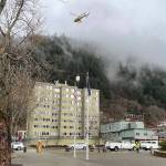 Workers in safety gear direct road traffic and the slinging of ATT telecommunications equipment via helicopter from a staging area to the rooftop of the Marine View building. (Laurie Craig / Juneau Empire)