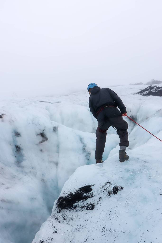 Þorsteinn Þorsteinsson looks at a moulin on the Sólheimajökull glacier on Oct. 20. A moulin, or glacier mill, is a crevasse through which water enters a glacier from the surface. (Jasz Garrett / For the Juneau Empire)