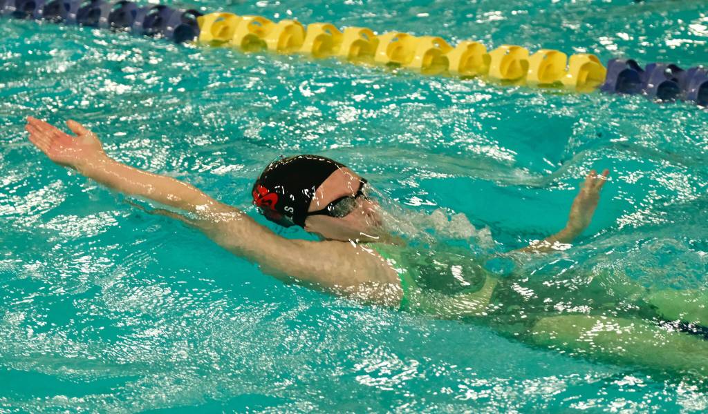 Juneau-Douglas High School: Yadaa.at Kalé junior Deedee Mills breaks the surface in the girls 100 yard backstroke final during the ASAA Swim & Dive State Championships on Saturday at Anchorages Bartlett High School pool. (Klas Stolpe / Juneau Empire)