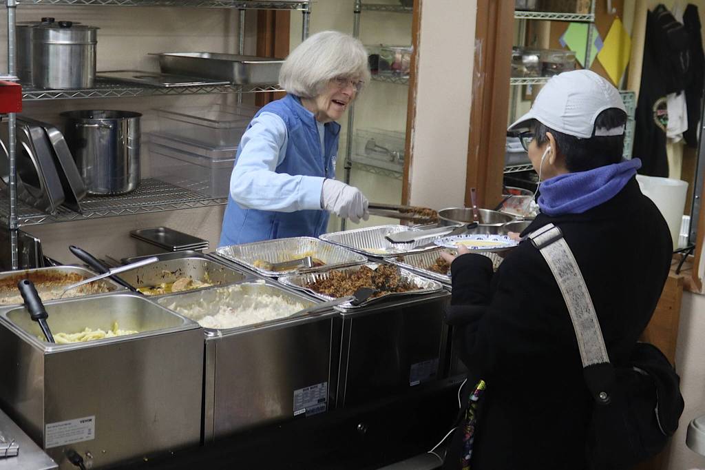 Julie Neyhart, a member of Resurrection Lutheran Church for the past 20 years, serves a hot meal to a guest during the churchs weekly food pantry on Tuesday. (Mark Sabbatini / Juneau Empire)
