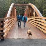 Maple the dog leads Kerry Lear and Stephanie Allison across the newly completed Kaxdigoowu Heen Dei (also known as the Brotherhood Bridge Trail) over Montana Creek Monday, November 11. (Laurie Craig / Juneau Empire)