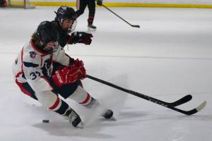 Juneau-Douglas High School: Yadaa.at Kalé senior Emilio Holbrook battles for a puck with North Pole junior Hunter Simons (37) during the Crimson Bears 5-2 loss to the Patriots on Saturday at the Treadwell Ice Arena. (Klas Stolpe / Juneau Empire)