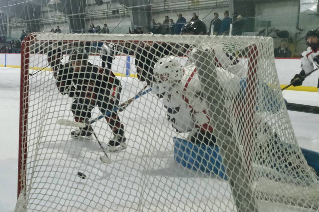 Juneau-Douglas High School: Yadaa.at Kalé sophomore Tricen Headings (34) pokes in his first career varsity goal past North Pole junior goalie Daniel Rady (74) during the Crimson Bears 5-2 loss to the Patriots on Saturday at the Treadwell Ice Arena. (Klas Stolpe / Juneau Empire)