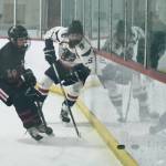 Juneau-Douglas High School: Yadaa.at Kalé freshman Summit Bos (14) works for a puck against North Pole junior Sam Lannet (15) during the Crimson Bears 5-2 loss to the Patriots on Saturday at the Treadwell Ice Arena. (Klas Stolpe / Juneau Empire)