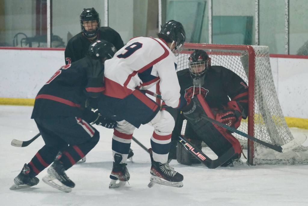 Juneau-Douglas High School: Yadaa.at Kalé senior goalie Caleb Friend defends the net as JDHS senior Carter Miller (6), junior Paxton Mertl (7) and North Pole senior Kagen Kramer (9) battle for the puck during the Crimson Bears 5-2 loss to the Patriots on Saturday at the Treadwell Ice Arena. (Klas Stolpe / Juneau Empire)