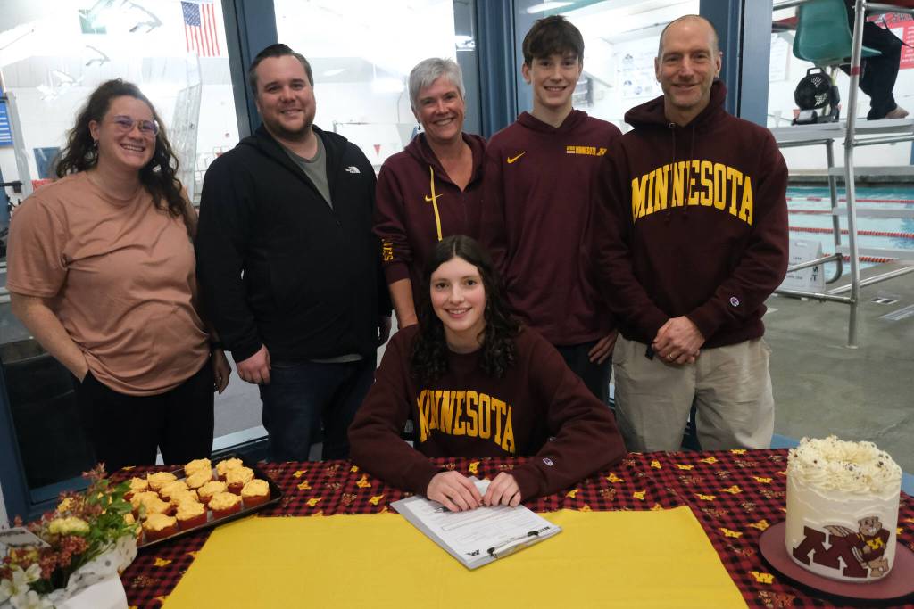 Juneau-Douglas High School: Yadaa.at Kalé senior Emma Fellman, seated, swim coaches Amber Kelly and Seth Cayce, mother Cheryl Fellman, brother Logan Fellman and father Jason Fellman during Emmas letter of intent signing to the University of Minnesota on Thursday at Augustus Brown Pool. (Klas Stolpe / Juneau Empire)