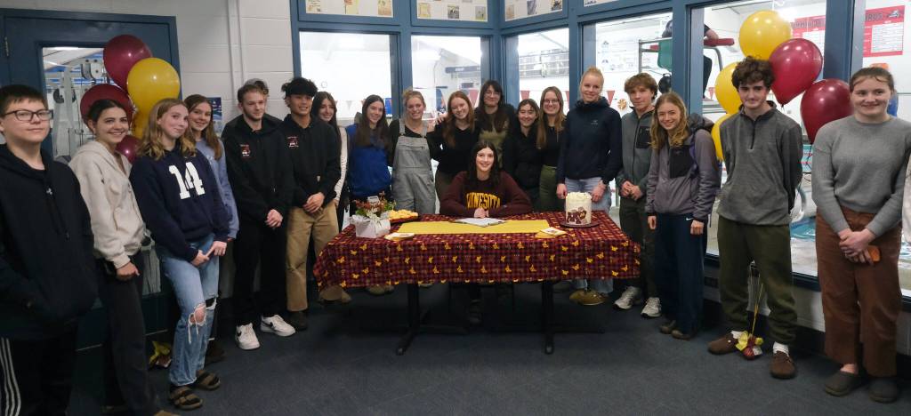 Friends and teammates of Juneau-Douglas High School: Yadaa.at Kalé senior Emma Fellman, seated, during her letter of intent signing to the University of Minnesota on Thursday at Augustus Brown Pool. (Klas Stolpe / Juneau Empire)