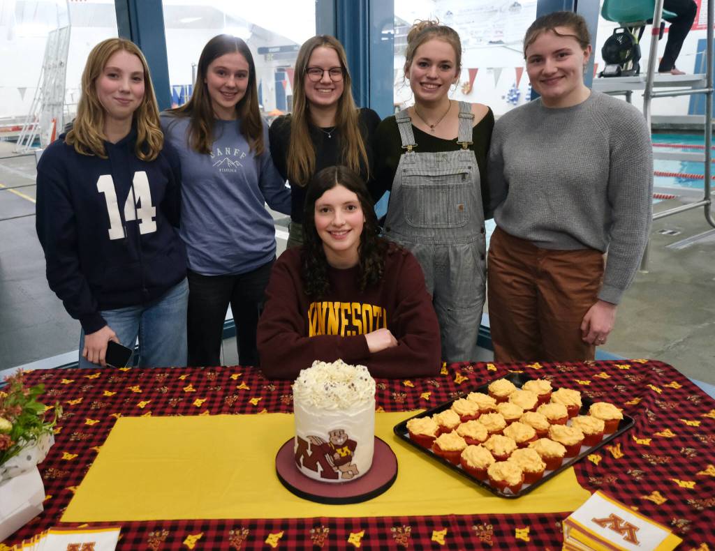 Juneau-Douglas High School: Yadaa.at Kalé senior Emma Fellman, seated, is joined by swimmates, left-to-right, sophomore Lily Francis, junior Valerie Peimann, senior Lucia Chapell, senior Pacific Ricke and senior Parker Boman during Emmas letter of intent signing to the University of Minnesota on Thursday at Augustus Brown Pool. (Klas Stolpe / Juneau Empire)