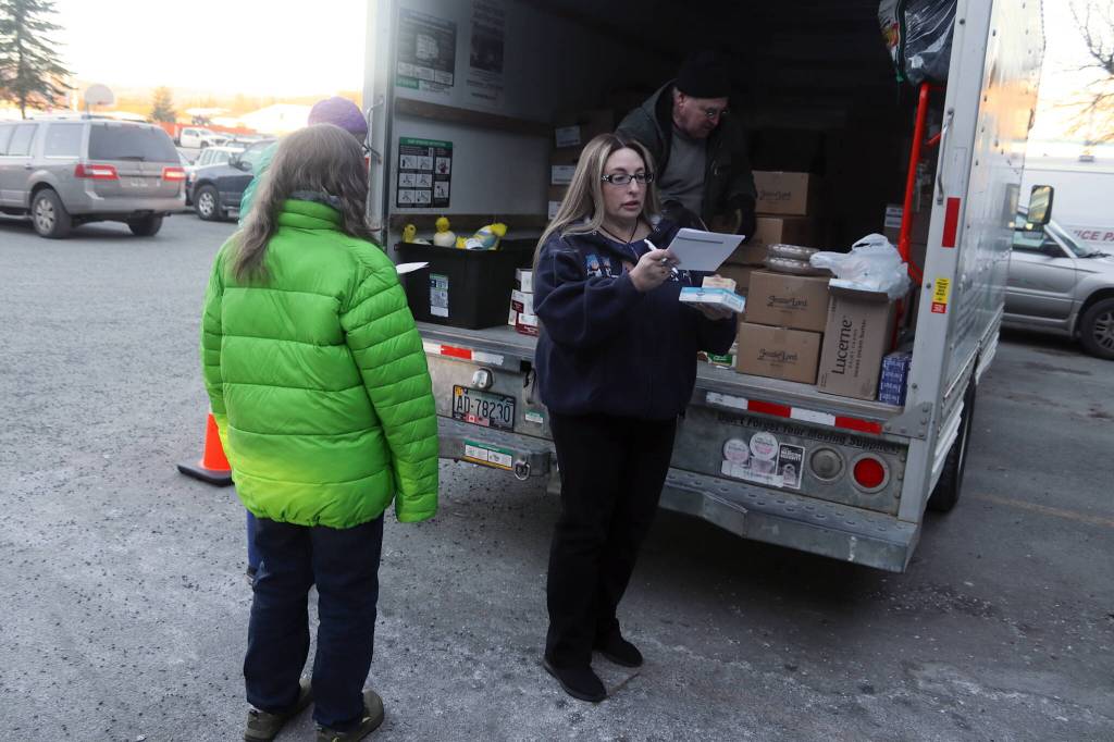 Rachel Ceja makes sure she has all of the items on her delivery list in the parking lot of St. Vincent de Paul Juneaus Teal Street complex before setting out to deliver Thanksgiving food baskets on Saturday morning. (Mark Sabbatini / Juneau Empire)