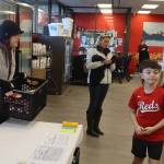 Kelly Moore (left), a board member of the Southeast Alaska Food Bank, accepts a crate of donated food from Kalon Herman, 9, at Super Bear IGA on Saturday morning as part of the food banks annual Caring is Sharing Food Drive. (Mark Sabbatini / Juneau Empire)