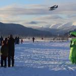 A floatplane passes above a fluorescent green dinosaur and lots of humans gathered for the annual Turkey Trot 5K and 1 Mile Fun Run on Thursday along the Airport Dike Trail. (Mark Sabbatini / Juneau Empire)