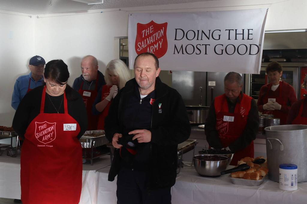 Petr Janousek (center), co-leader of The Salvation Army Juneau Corps, says grace before the organizations annual communal Thanksgiving Day at the Juneau Yacht Club. (Mark Sabbatini / Juneau Empire)