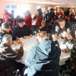 William James (standing) hands plates of Thanksgiving food to family members during a communal holiday meal hosted by The Salvation Army Juneau Corps on Thursday at the Juneau Yacht Club. (Mark Sabbatini / Juneau Empire)