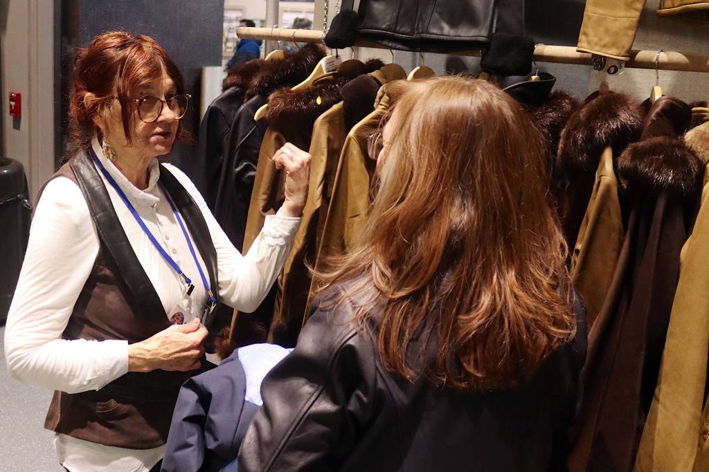 Bridget Milligan, a former Juneau resident now living in Hawaii, shows a customer leather jackets she sold at her Kodiak Coats shop before closing it in 2013. This is her first return trip to the public market since her departure. (Mark Sabbatini / Juneau Empire)