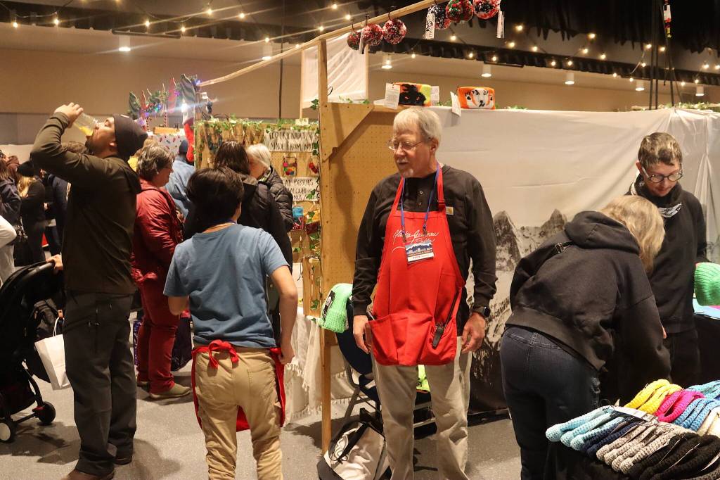 Peter Metcalfe, longtime organizer of the Juneau Public Market, greets a helper in the main ballroom at Centennial Hall on Friday. (Mark Sabbatini / Juneau Empire)