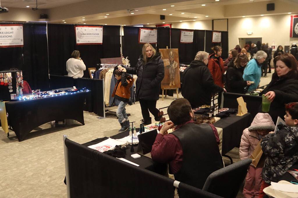 Shoppers examine the vendor booths at the Indigenous Artists and Vendors Holiday Market at Elizabeth Peratrovich Hall on Friday. The market, matching the days of the Juneau Public Market, is scheduled to be open noon to 5 p.m. through Sunday. (Mark Sabbatini / Juneau Empire)