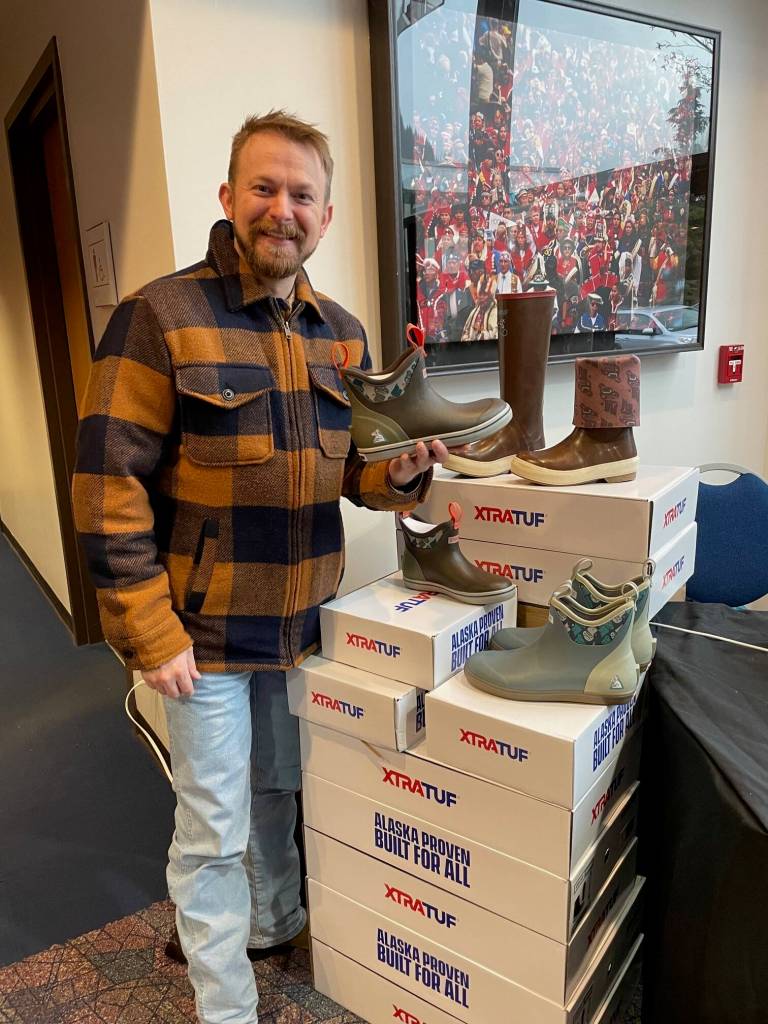 Zak Kirkpatrick, chief marketing officer for Allen Marine Tours, displays a special edition rubber boot with Mary Goddards Alaska Native design pattern on the lining. (Laurie Craig / Juneau Empire)