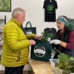 Retired chef Kirk Stagg picks up a bag of fresh edible greens from Amy White at Juneau Greens new storefront. (Laurie Craig / Juneau Empire)