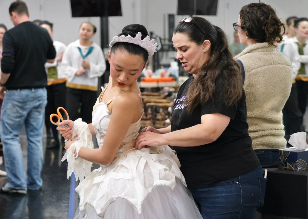 Snow Corps dancer Khloe Guevarra receives costume help from JDT executive director Bridget Lujan during Juneau Dance Theatres The Nutcracker dress rehearsal Sunday at the JDT studio. (Klas Stolpe / Juneau Empire)
