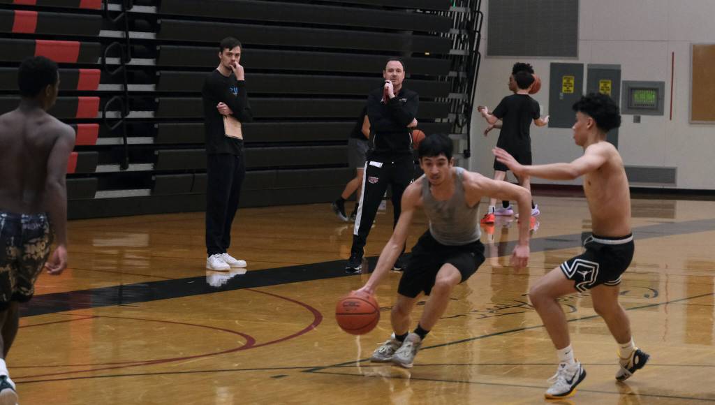 Juneau-Douglas High School: Yadaa.at Kalé boys head coach Robert Casperson, right, and assistant Kaleb Tompkins, left, watch a scrimmage game during the first day of Crimson Bears varsity basketball tryouts Wednesday at the George Houston Gymnasium. (Klas Stolpe / Juneau Empire)