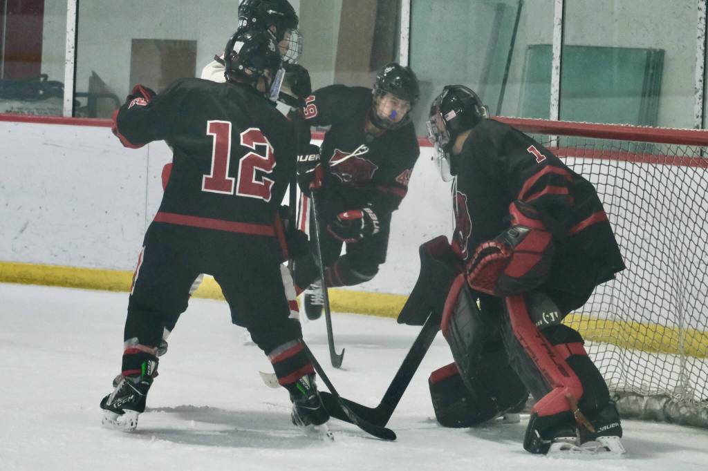 Juneau-Douglas High School: Yadaa.at Kalé senior goalie Caleb Friend (1) closes off the goal as junior Emerson Newell (12) and sophomore Bryden Roberts (49) work to move the puck away against North Pole earlier this season. Friend had two perfect sheets in wins over Kodiak this weekend. (Klas Stolpe / Juneau Empire file photo)