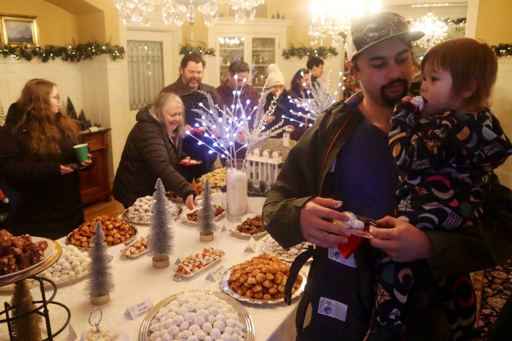 James Cheng, and his daughter Gwen, 1, help themselves to some of the 17,050 cookies being offered to visitors during the annual Holiday Open House at the Governors Residence on Tuesday. (Mark Sabbatini / Juneau Empire)