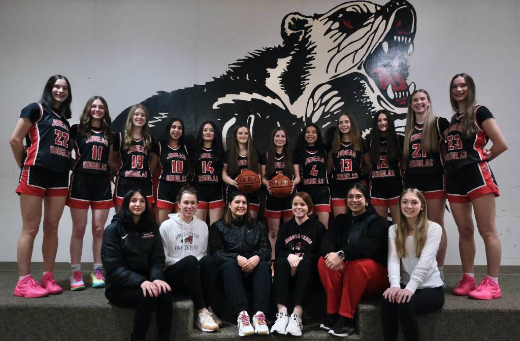 The 2024-25 Juneau-Douglas High School: Yadaa.at Kalé Crimson Bears Girls Basketball team. Standing, from left-to-right, senior Kerra Baxter (22), junior Gwen Nizich (11), freshman Lydia Goins (15), senior Addison Wilson (10), sophomore Layla Tokuoka (14), junior Cambry Lockhart (3), sophomore June Troxel (5), senior Mary Johnson (4), freshman Sadie Lockhart (13), sophomore Bergen Erickson (12), freshman Athena Warr (21) and senior Cailynn Baxter (23). Seated l-r: Senior manager Nadia Wilson, head coach Tanya Nizich, assistant coaches Jasmine James, Angie Kemp, Nicole Fenumiai, and junior manager Jadyn Cook. (Klas Stolpe / Juneau Empire)