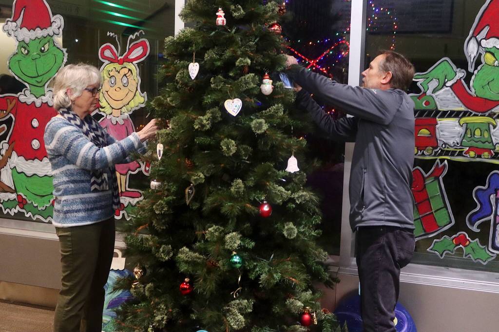 Pat McLear (left) and Taylor Dunn hang hand-decorated memorial ornaments on a Christmas tree during a Light Up a Life community celebration hosted by the hospitals Home Health and Hospice program Friday evening. (Mark Sabbatini / Juneau Empire)