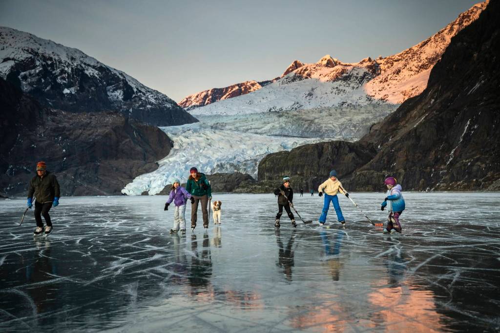 A family ice skates and perfects their hockey prowess on Mendenhall Lake, below Mendenhall Glacier, outside of Juneau, Alaska, Nov. 24, 2024. The states capital, a popular cruise port in summer, becomes a bargain-seekers base for skiing, skating, hiking and glacier-gazing in the winter off-season. (Christopher S. Miller/The New York Times)