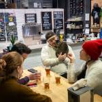 At the Barnaby Brewing Company, the owners cat, Simcoe, cuddles with a bartender enjoying a beer with friends, in Juneau, Alaska, Nov. 30, 2024. The states capital, a popular cruise port in summer, becomes a bargain-seekers base for skiing, skating, hiking and glacier-gazing in the winter off-season. (Christopher S. Miller/The New York Times)