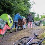 Christopher Moore helps another Juneau homeless resident wheel her belongings from a makeshift campsite on private property near the airport on July 15. (Jasz Garrett / Juneau Empire file photo)