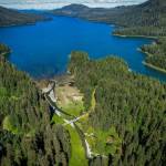 An aerial view of Láan Yík (Channel inside or Port Camden) with cars and people gathered on the bridge over Yéil Héeni (Ravens Creek) during a May 2024 convening on Kuiu Island. Partners that comprise the Ḵéex̱ Ḵwáan Community Forest Partnership and staff from the Tongass National Forest met to discuss priorities for land use, stream restoration, and existing infrastructure on the north Kuiu road system. (Photo by Lee House)