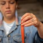 Marina Anderson slices salmon into strips on a table by her familys smokehouse. Anderson shows the strip to youth crew members from the Prince of Wales Alaska Youth Stewards crew who had caught the salmon the day prior, were learning to process the fish and would eventually share through community distribution. (Photo by Lee House)