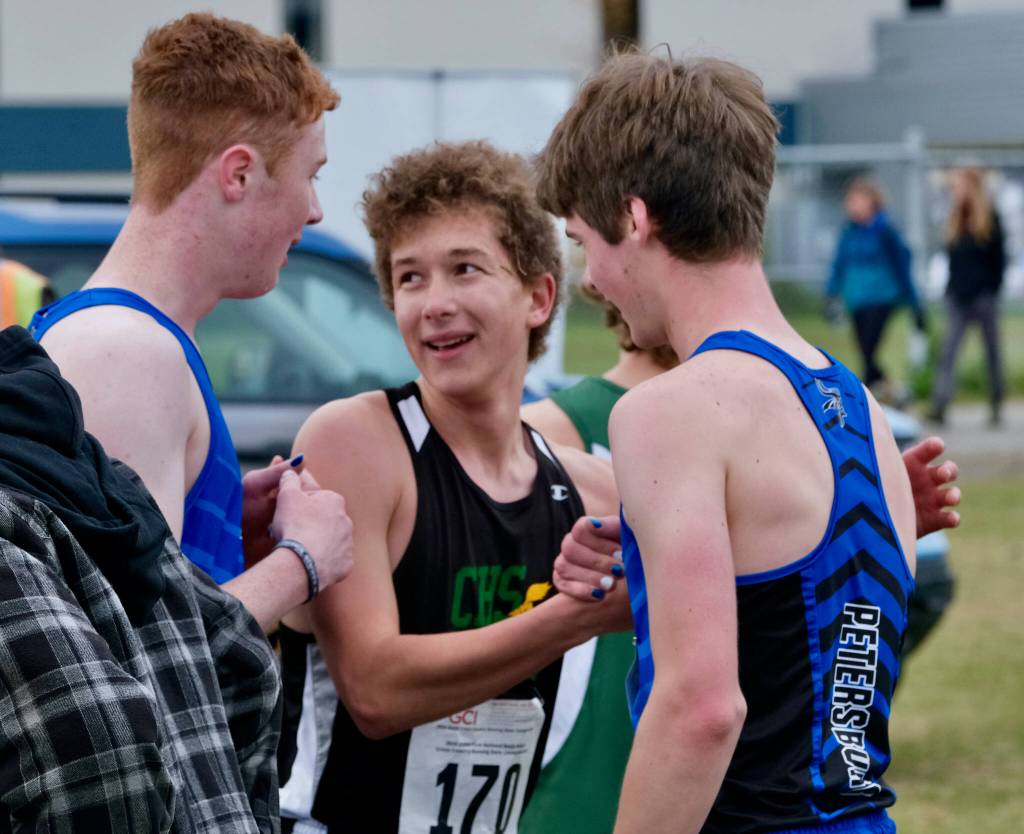 Petersburg junior Gaje Ventress and senior Elias Ward congratulate Craig sophomore Aulis Nelson (170) on his title win in the Division III boys 2024 ASAA cross-country running state championships in September on Anchorages Bartlett High School Trails. (Klas Stolpe / Juneau Empire file photo)