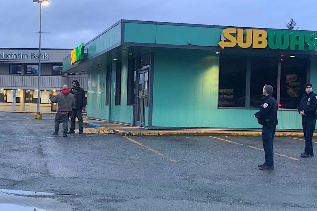Berton Tullis (wearing a black jacket at left) greets a man who got into an angry discussion with Juneau Police Department officers following the fatal shooting of a woman by an officer near the Nugget Mall on Wednesday morning. Both men left the scene peacefully. (Mark Sabbatini / Juneau Empire)