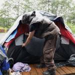 Ashley Rae Johnston zips up her tent at the now-closed Mill Campground on Aug. 15, 2023, as she prepares for the two-mile walk to a local food pantry with an empty suitcase. Johnston was killed while carrying a hatchet in a confrontation with police on Christmas Day of this year. (Clarise Larson / Juneau Empire file photo)
