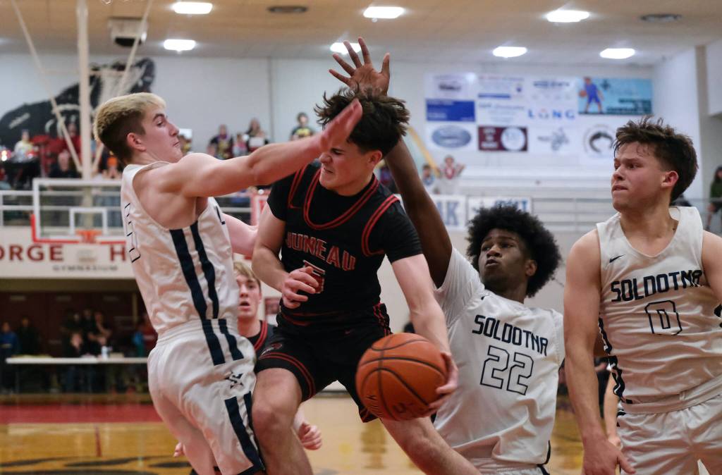 Juneau-Douglas High School: Yadaa.at Kalé junior Brandon Casperson (5) passes under pressure from Soldotna junior Bryan Berg (5), sophomore Damari Adams (22) and senior Easton Hawkins (0) in the Crimson Bears 62-60 overtime loss to the Stars during Saturday action at the George Houston Capital City Classic in Juneau. (Klas Stolpe / Juneau Empire)
