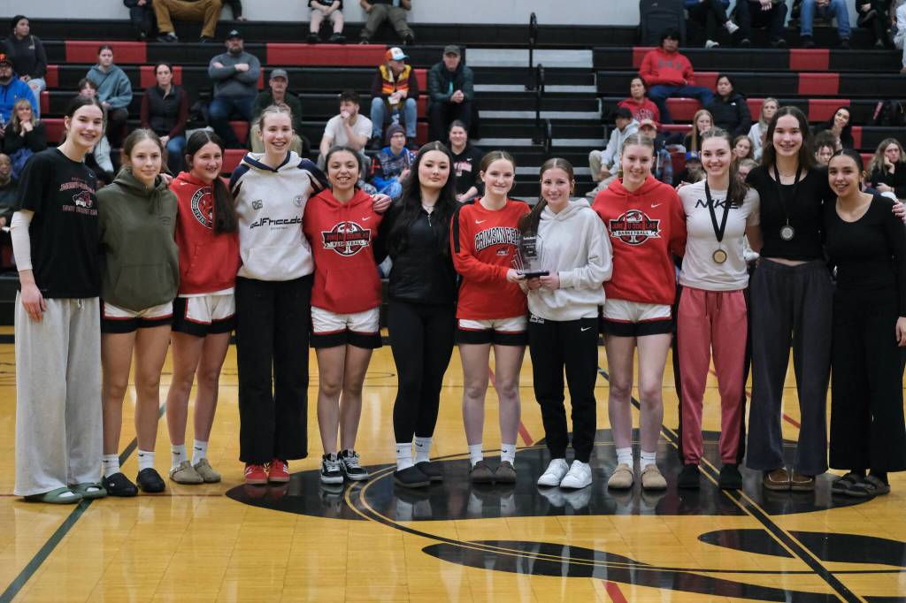The Juneau-Douglas High School: Yadaa.at Kalé Crimson Bears girls basketball team pose with their championship trophy at the George Houston Capital City Classic on Sunday. (Klas Stolpe / Juneau Empire)