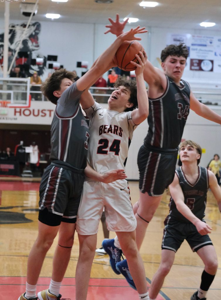 Juneau-Douglas High School: Yadaa.at Kalé sophomore Logan Carriker (24) powers a shot against Ketchikan seniors Jonathan Scoblic (3) and Marcus Stockhausen (34) during the Crimson Bears’ 70-63 loss to the Kings on Saturday at the George Houston Gymnasium in Juneau. (Klas Stolpe / Juneau Empire)