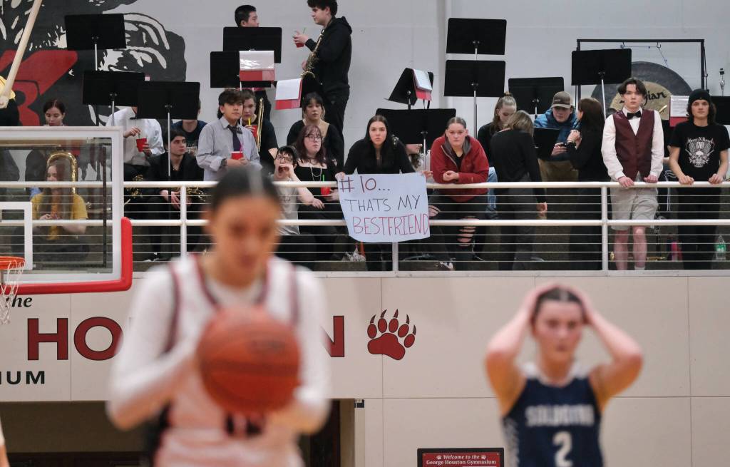A Juneau-Douglas High School: Yadaa.at Kalé Pep Band fan of senior Addison Wilson watches as she shoots a free throw during the Crimson Bears 65-28 win over the Stars on Friday at the George Houston Gymnasium. (Klas Stolpe / Juneau Empire)