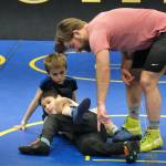 Askren Wrestling Academy coach Wilder Wichman helps Garrett Reid and Rylan Pegues learn a technique on Monday during a three-day wrestling clinic at the Juneau Wrestling Center. (Klas Stolpe / Juneau Empire)