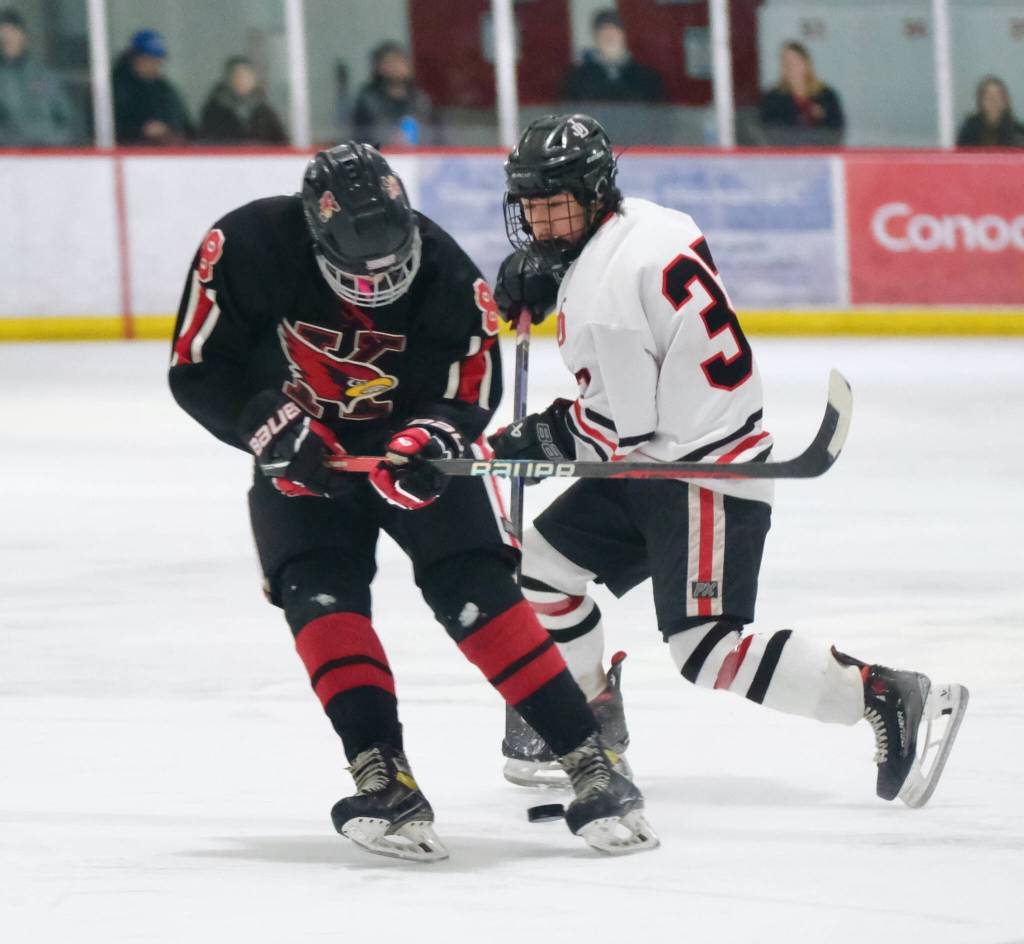 Juneau-Douglas High School: Yadaa.at Kalé senior Emilio Holbrook (37) moves a puck against Kenais Everett Chamberlain (8) during the Crimson Bears 5-1 loss to the Kardinals on Saturday at Treadwell Ice Arena. (Klas Stolpe / Juneau Empire)