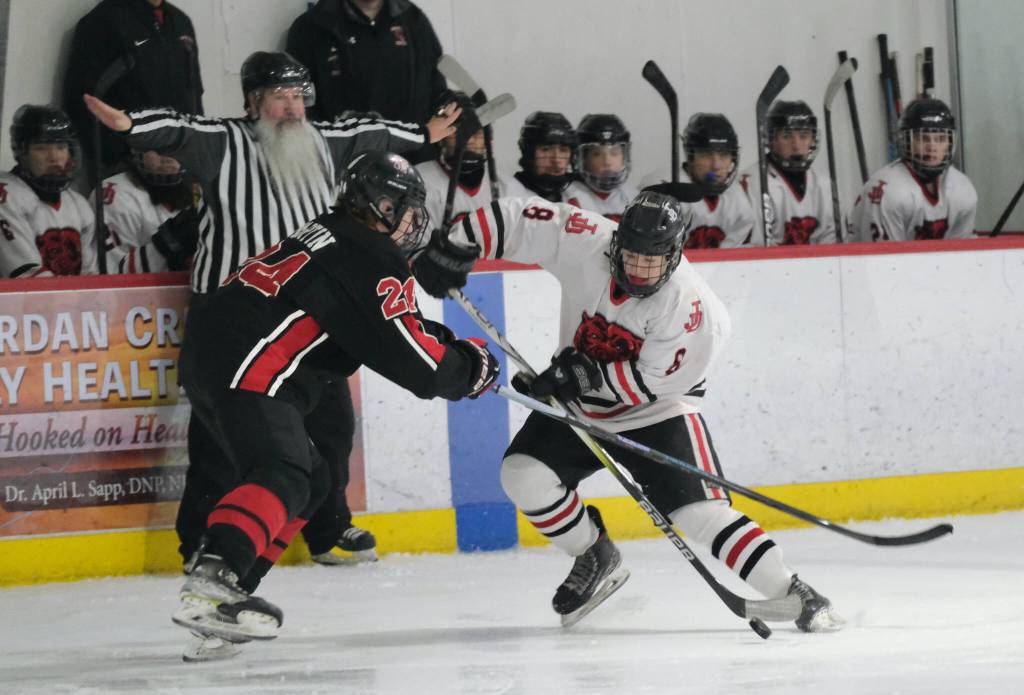 Juneau-Douglas High School: Yadaa.at Kalé senior Zander Smith (8) moves a puck against Kenais Avery Martin (24) during the Crimson Bears 5-1 loss to the Kardinals on Saturday at Treadwell Ice Arena. (Klas Stolpe / Juneau Empire)
