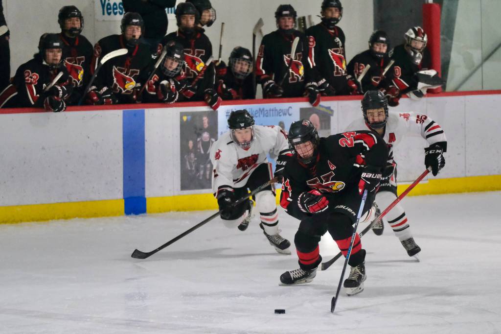 Juneau-Douglas High School: Yadaa.at Kalé junior Emerson Newell (12) and senior Dylan Sowa (35) chase Kenais Avery Martin (24) during the Crimson Bears 5-1 loss to the Kardinals on Saturday at Treadwell Ice Arena. (Klas Stolpe / Juneau Empire)