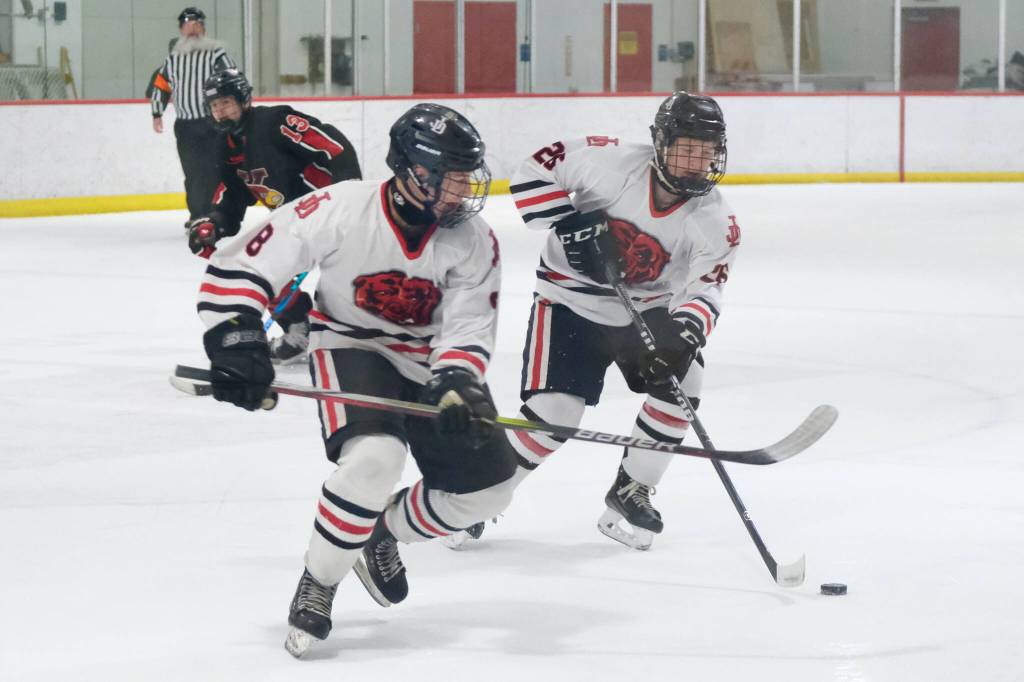 Juneau-Douglas High School: Yadaa.at Kalé seniors Zander Smith (8) and Loren Platt (26) control a puck during the Crimson Bears 5-4 loss to the Kardinals on Friday at Treadwell Ice Arena. The teams play Saturday at 8:30 a.m. (Klas Stolpe / Juneau Empire)