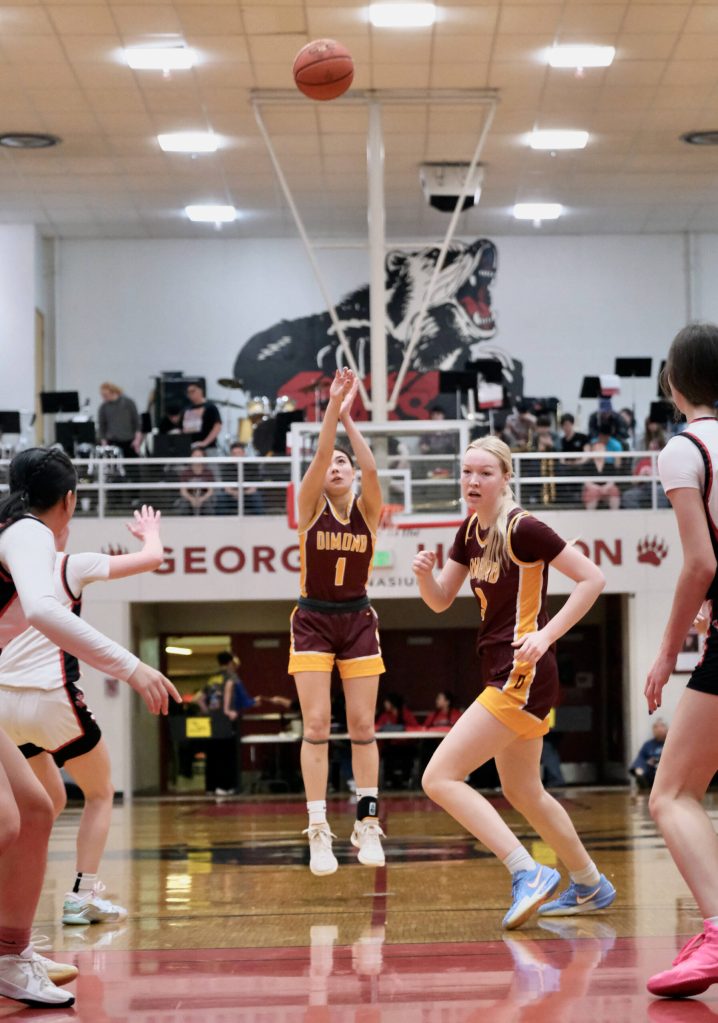 Dimond senior Mecca Goldsberry (1) shoots as senior Evan Hamey (3) moves to the basket during the Lynx 53-43 win over the Juneau-Douglas High School: Yadaa.at Kalé Crimson Bears on Saturday in the George Houston Gymnasium. (Klas Stolpe / Juneau Empire)