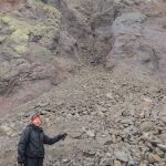Ned Rozell pauses at the site of a rock avalanche on St. Matthew Island in the Bering Sea during a 2012 visit. (Photo by Rich Kleinleder)