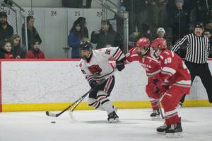 Juneau-Douglas High School: Yadaa.at Kalé senior Matthew Plang (22) skates away from Wasilla senior Karson McGrew (18) and freshman Dylan Mead (49) during the Crimson Bears 3-1 win over the Warriors at Treadwell Ice Arena on Saturday. (Klas Stolpe / Juneau Empire)