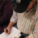 Steve Bower signs an objection to the river barriers after giving public testimony to the Juneau Assembly on Feb. 3, 2025. (Jasz Garrett / Juneau Empire)